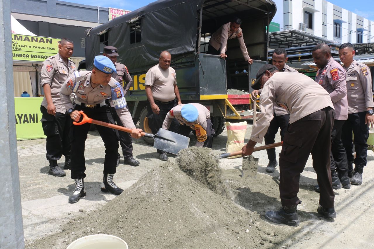 Tampak personel Polres Jayapura mengaduk campuran semen untuk menutup jalan berlubang di turunan gunung merah Sentani