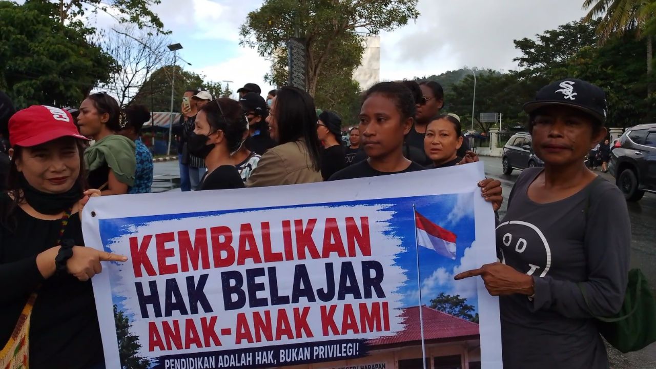 Tampak para orang tua siswa membentangkan spanduk bertuliskan "Kembalikan Gak Belajar Anak-Anak Kami"